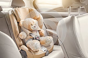 Baby child seat car. A beige teddy bear is fastened with seat belts in a car seat. Travel by car