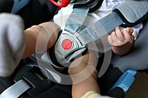 Baby child sitting in car seat with safety belt locked