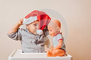 Baby in Christmas bonnet dressing up the doll , on white background. copy space