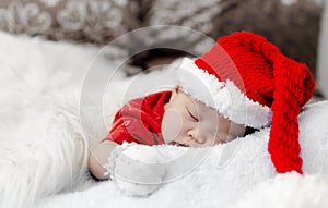 baby in christmas santa costume sleeping on bed