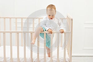 Baby climbs out of the crib, baby boy 2 years old in the crib