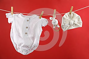 Baby clothes and accessories hanging on washing line against red
