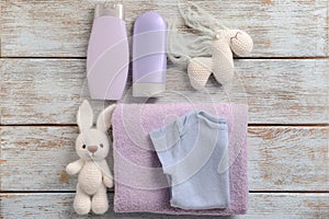 Baby clothes, bath cosmetics, towel and toys on wooden background