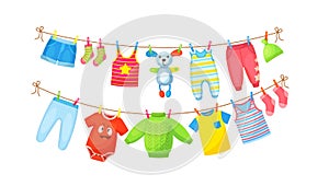 Baby clothes hanging on clothesline. Drying children`s clothes and accessories after washing on rope. Shorts, socks, romper,