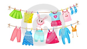 Baby clothes hanging on clothesline. Drying children`s clothes and accessories after washing on rope. Shorts, socks, romper,