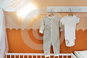 Baby clothes hanging over the crib. Minimalist style children's room interior