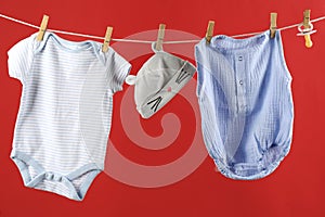 Baby clothes hanging on washing line against red background