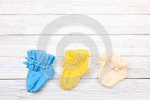 Baby clothes knitted booties on a white wooden background. View from above - Image