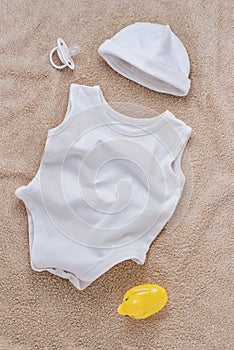 Baby clothes and pacifier on soft towel