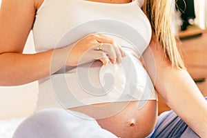 Baby clothes pregnant woman. Beautiful pregnancy mother with yellow baby clothes. Pregnant woman hugging belly and