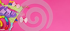 Baby clothes, rattles, feeding spoon on pink background Flatley . Horizontal banner. Copy space for text