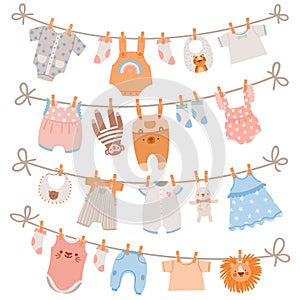 Baby clothes on rope. Newborn children apparel, socks, dress and toys hanging on clothesline. Kids laundry drying on