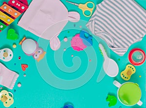 Baby clothes, soother, spoon, brush and toys over green background