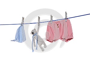 Baby clothes and toy bear drying on laundry line against background