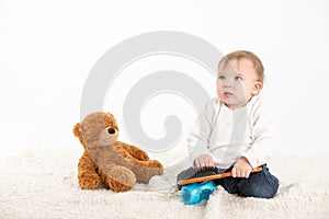 Baby combing his hair with a teddy bear by his side