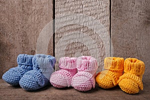 Baby concept: different colored baby booties, Three pairs of baby booties on a wooden background.