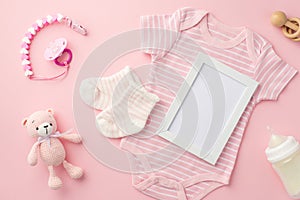 Baby concept. Top view photo of photo frame pink infant clothes bodysuit socks baby`s dummy chain bottle wooden rattle and knitte