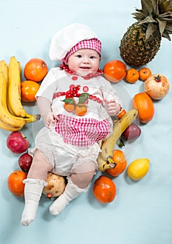 Baby cook girl wearing chef hat with fresh fruits.