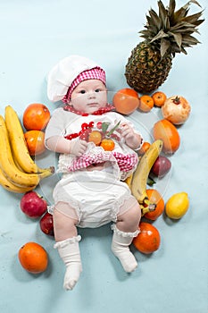 Baby cook girl wearing chef hat with fresh fruits.