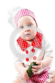 Baby cook girl wearing chef hat with fresh vegetables and fruits.