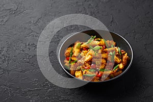 Baby Corn Manchurian dry looks like Schezwan Baby Corn in black bowl at dark slate background