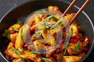 Baby Corn Manchurian dry looks like Schezwan Baby Corn in black bowl at dark slate background