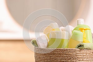 Baby cosmetic products and bath accessories in wicker basket indoors, closeup. Space for text