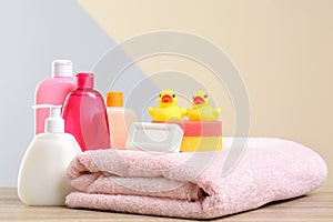 Baby cosmetic products, toys and towel on table against color