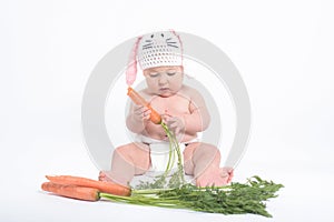 Baby in a costume of rabbit nibbling carrot