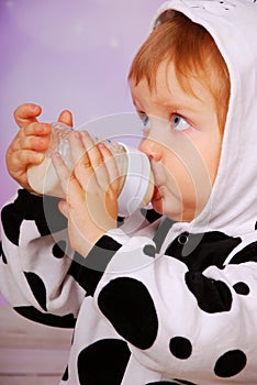 Baby in cow costume drinking milk from bottle