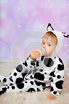 Baby in cow costume drinking milk from bottle