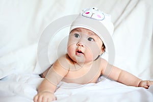 Baby with Cow Hat Lying Down on a White Blanket
