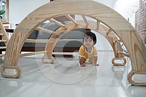 baby crawling past under the pikler climbing toys