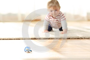 Baby crawling towards a dirty pacifier on the floor