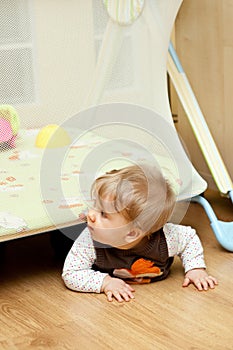 Baby crawling under playpen