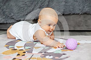Baby creep on floor of nursery grabbing colorful ball. Baby development. Sensory experience photo