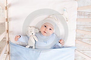 Baby in the crib at home in the morning or before going to bed, portrait, family and birth concept