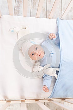 Baby in the crib at home in the morning or before going to bed, portrait, family and birth concept