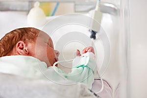 Baby in the crib of a hospital ICU room close-up