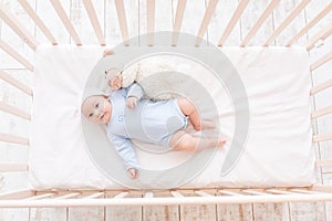 Baby in crib with teddy bear toy goes to bed or woke up in the morning, family and birth concept