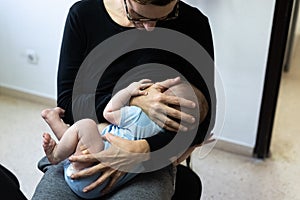 Baby crying after vaccination with band aid or plaster in the thigh, comforted by his mother who breastfeeds him photo