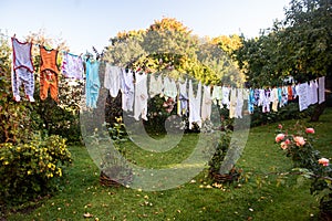 Baby cute clothes hanging on the clothesline outdoor. Child laundry hanging on line in garden