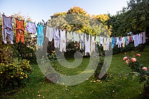 Baby cute clothes hanging on the clothesline outdoor. Child laundry hanging on line in garden