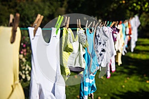 Baby cute clothes hanging on the clothesline outdoor. Child laundry hanging on line in garden