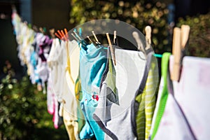 Baby cute clothes hanging on the clothesline outdoor. Child laundry hanging on line in garden