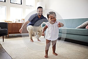 Baby Daughter Dancing With Father In Lounge At Home