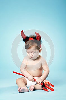 Baby with devil horns on blue background