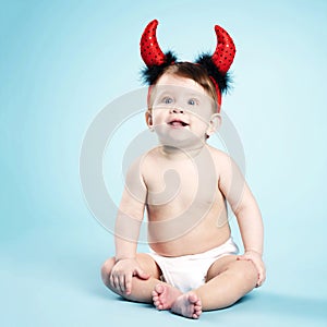 Baby with devil horns on blue background