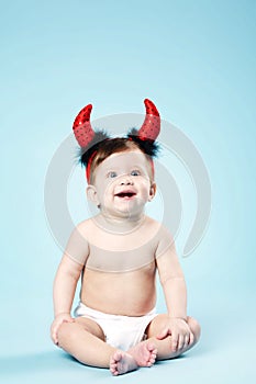 Baby with devil horns on blue background