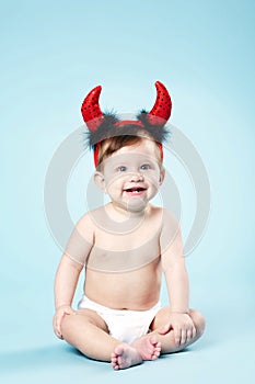 Baby with devil horns on blue background